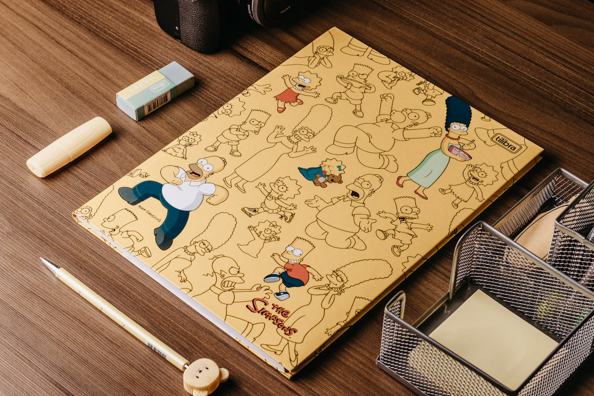 a wooden table topped with a notebook covered in cartoon characters