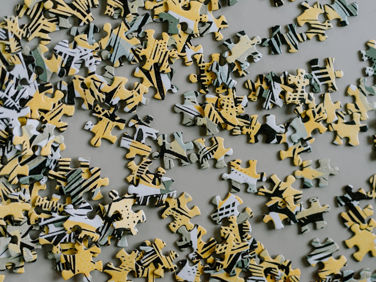 Scattered puzzle pieces with yellow and grey abstract patterns.