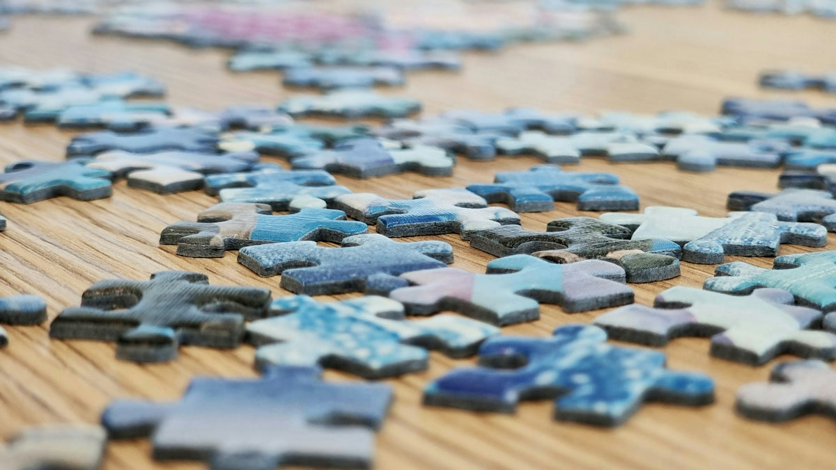 Scattered blue puzzle pieces on a wooden surface